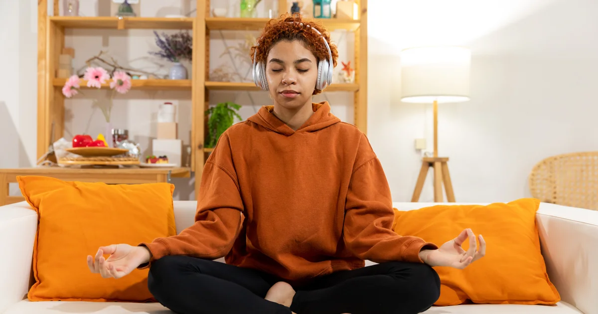 mulher sentada no sofá praticando meditação guiada para iniciantes