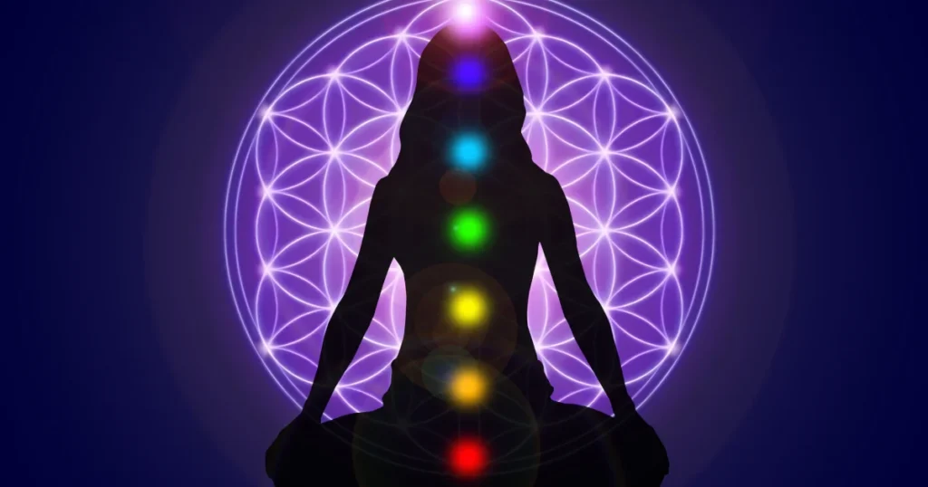 figura humana em postura de meditação com representação de 7 chakras